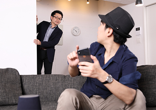 山田井さんがスマホを操作していると、後ろからトレンドマイクロの和田さんが現れ、それに気づいた写真